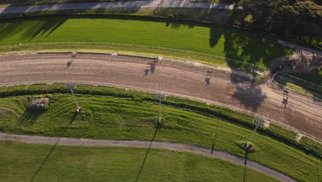 Toma-Aérea-De-Arriba-Hacia-Abajo-De-La-Ronda-De-Calentamiento-Durante-La-Competencia-De-Carreras-De-Caballos-En-San-Isidro,-Argentina