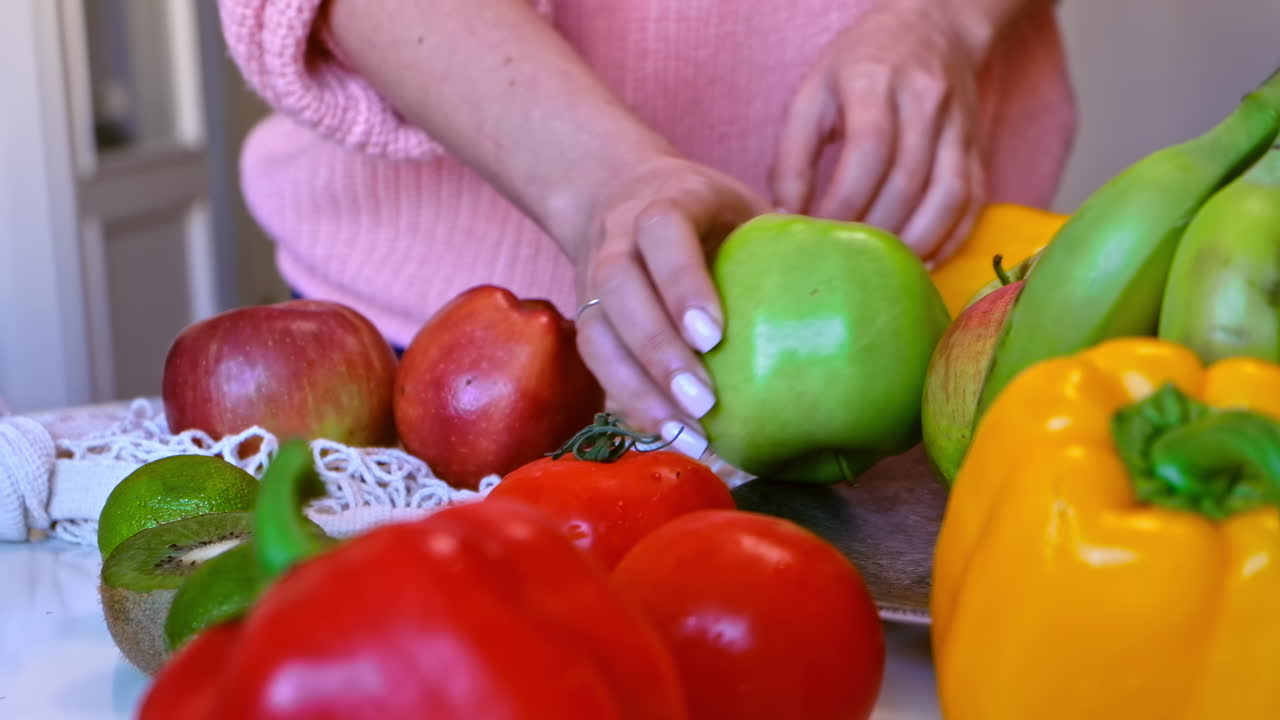 Woman's hands puts green and red apples from a grocery knitted eco bag on a plate