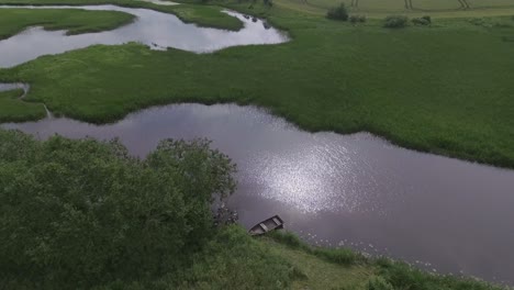 wooden boat in a winding river on a cloudy summer day