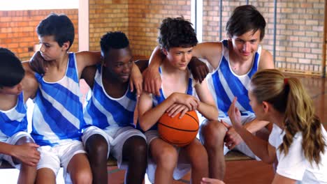 coach instructing a students in basketball court