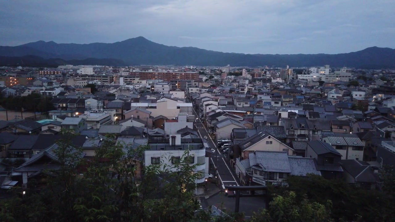 Vista aerea panoramica lenta della città di Kyoto al crepuscolo con montagne, Giappone, Ora Blu, quartiere giapponese, tetti e strade