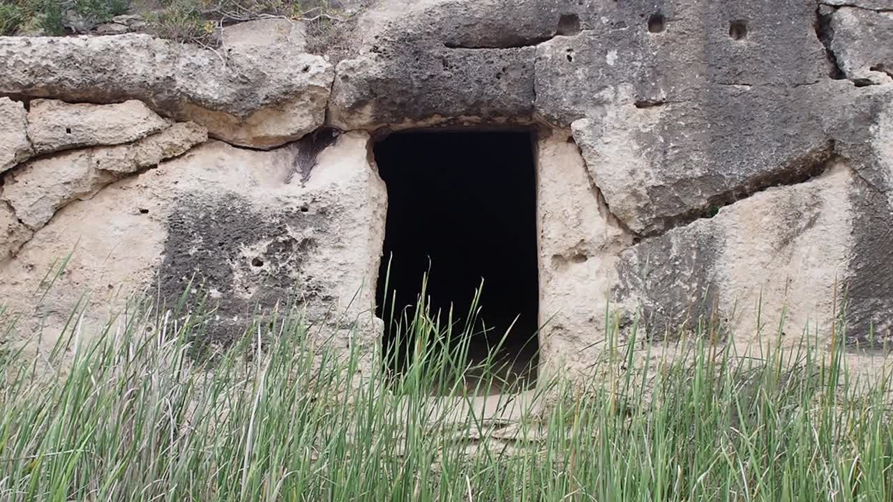 Ancient tomb entrance at Necropolis Cala Morell, Menorca, surrounded by grass
