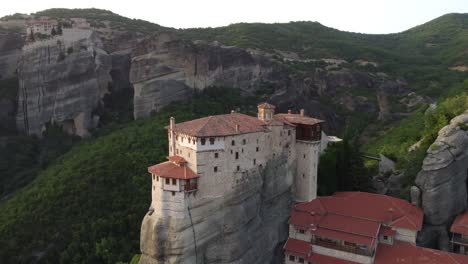 Meteora-Monasteries-in-Greece-at-sunset,-with-Landscape-scenery-and-green-hills,-Aerial-view