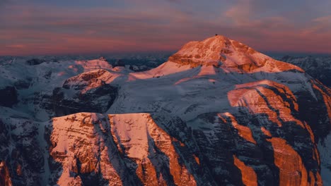 Drone-tilts-over-pink-cliffs-of-the-Dolomites-to-the-horizon