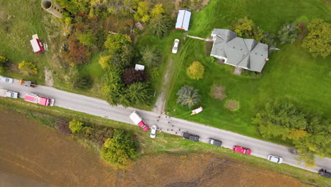 top down aerial orbital view of car traffic accident incident site at countryside road, first aid vehicles fire trucks and stationary cars along street roadside, green fields lands around