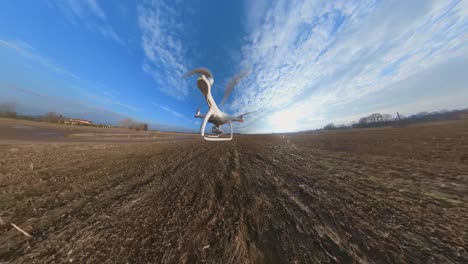 close-up side view of dji phantom 4 quadcopter drone flying forward over fields