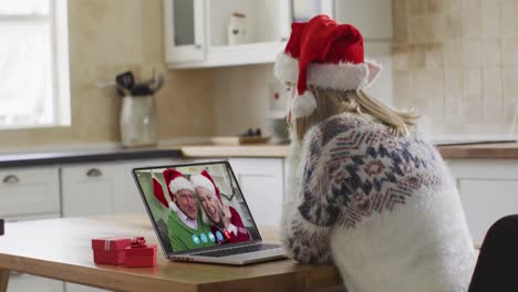 mujer caucásica con sombrero de papá noel en una videochat portátil durante la navidad en casa