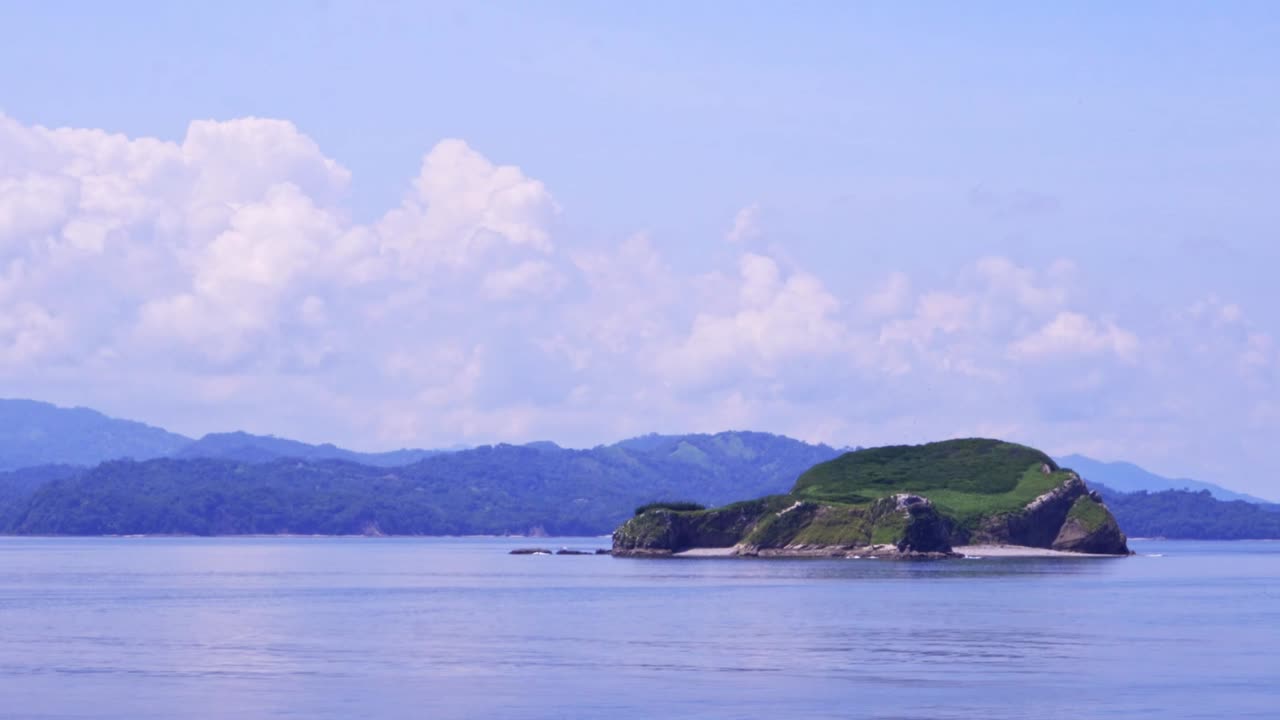 Passing Island with Mountains on the Horizon in Costa Rican Landscape on Sunny Day with cloudy Sky, Close Shot