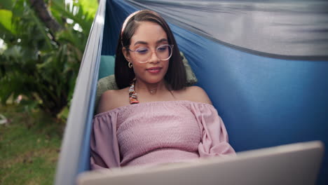 woman relaxing in a hammock with a laptop