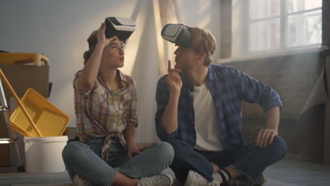 young couple in vr glasses discussing house renovation project in new house.