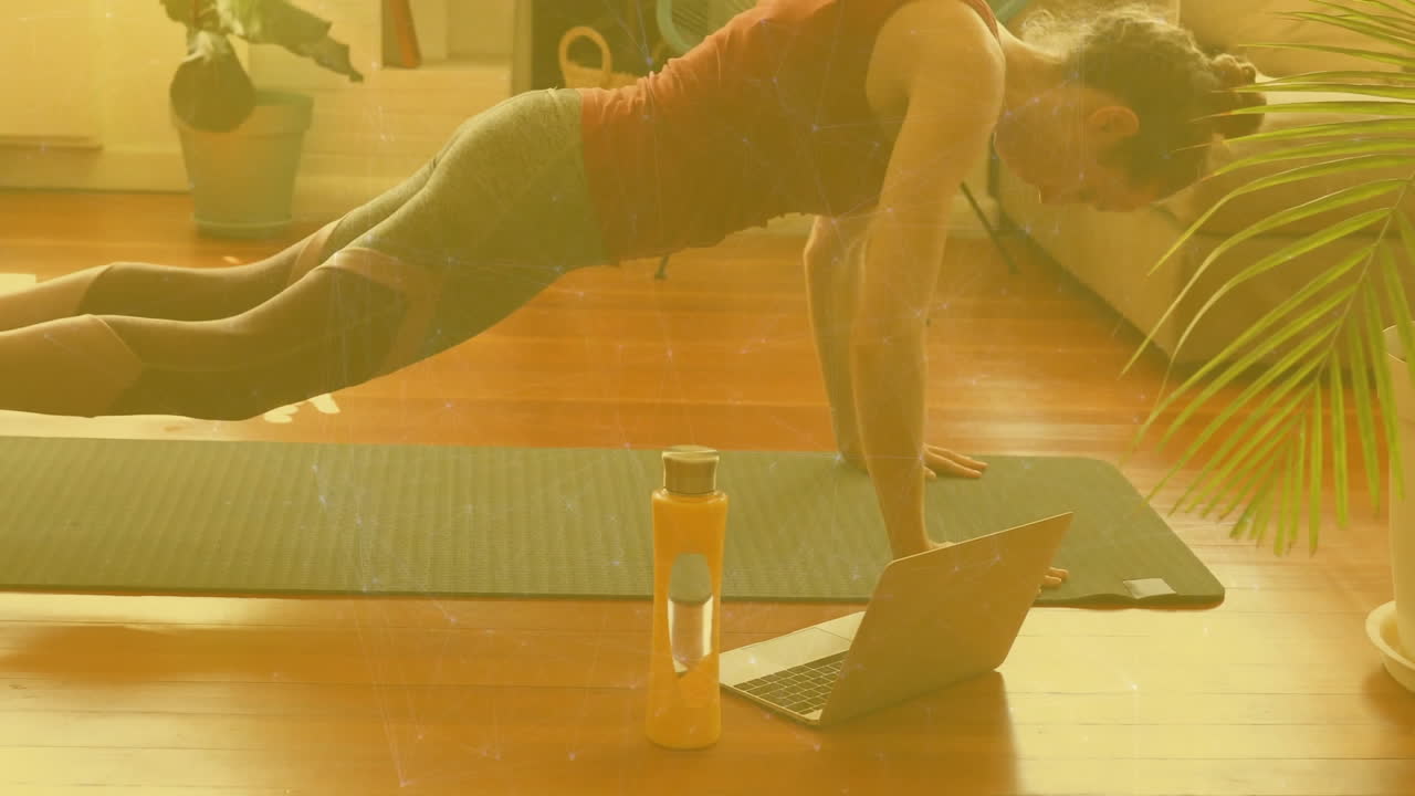 woman performing yoga in sunlit home workout space, floating animated fitness graph above laptop