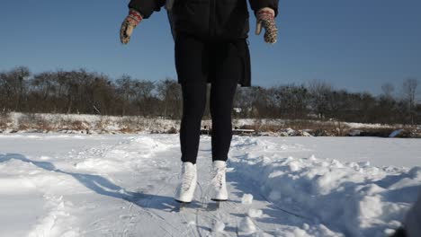 woman feet is ice skating on ice in winter. female skater is skating on frozen river. woman legs rides in skates on frozen lake. winter sport activities