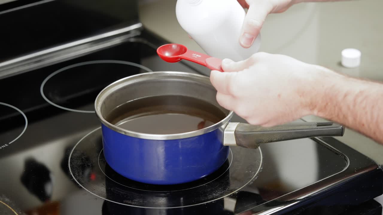 집에서 양초를 만들기 위해 녹인 왁스에 향기로운 에센셜 오일을 첨가합니다.