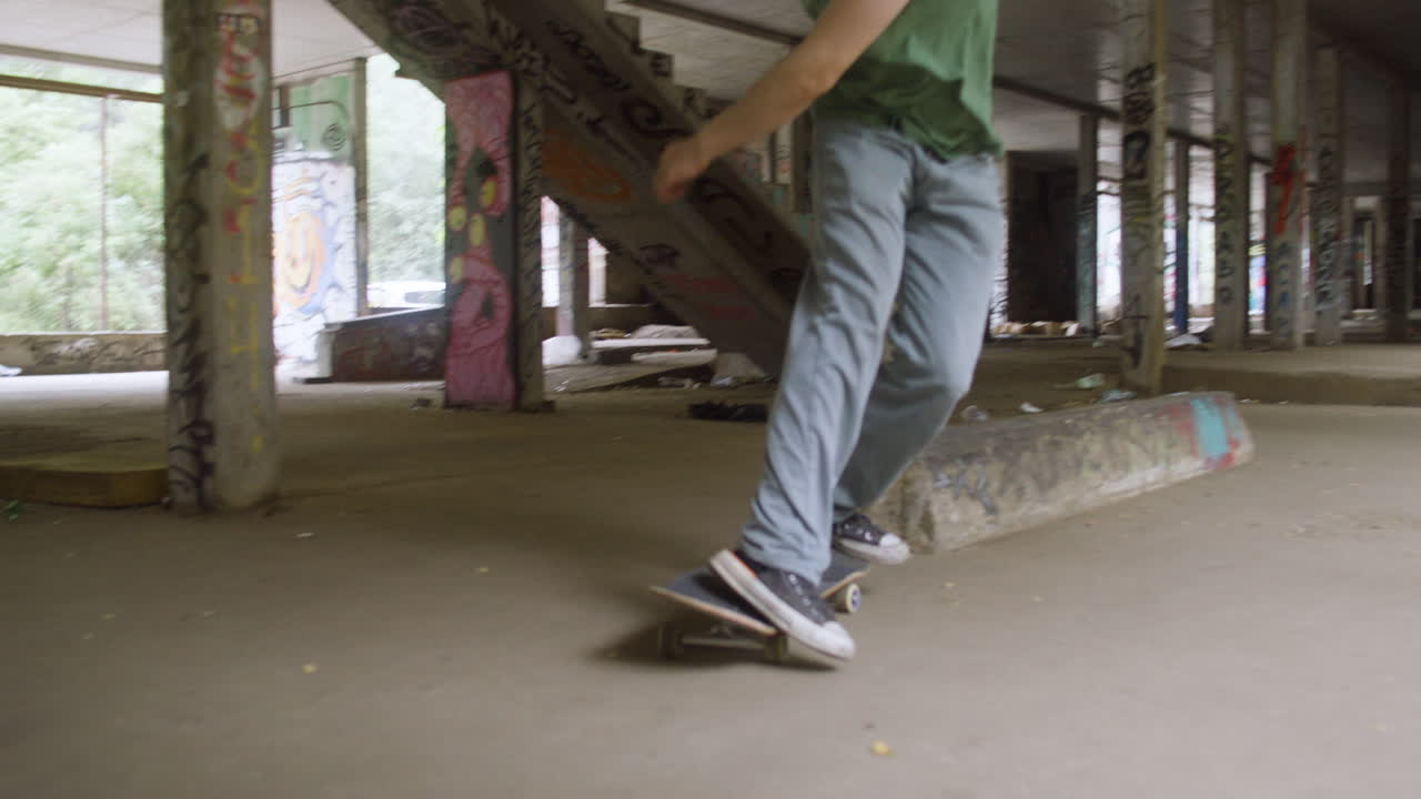 백인 소년이 폐허가 된 건물에서 스케이트보드를 타고 있습니다.