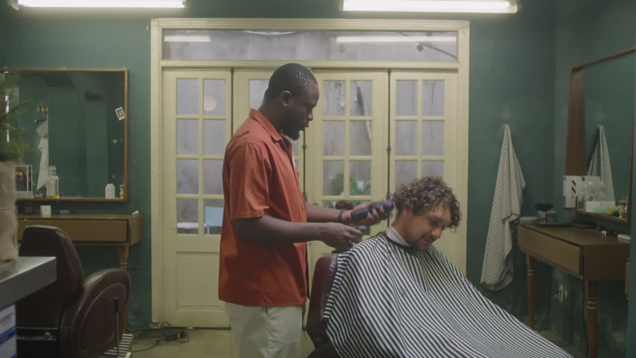 Black Barber Using Hair Clippers for Serving Male Client