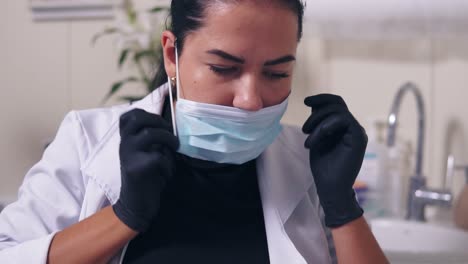 Professional-doctor-putting-on-her-medical-mask-while-preparation-to-procedures.-Healthcare-concept