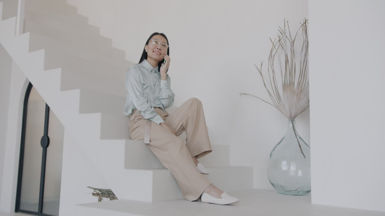 Woman talking on phone on stairs in modern home
