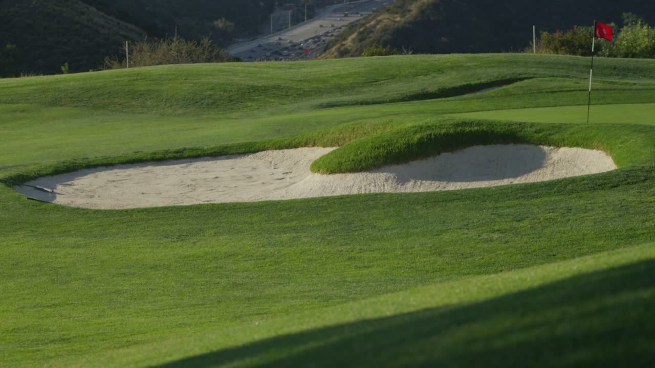 배경에 산이 있는 골프장에서 모래 함정의 넓은 전망