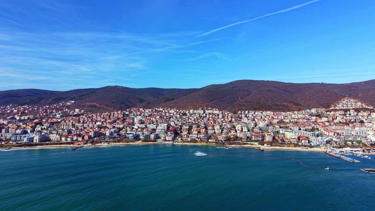 Vista costeira de uma cidade à beira-mar com edifícios ao longo da costa sob um céu azul claro