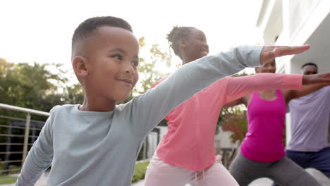 Happy-african-american-parents,-son-and-daughter-practicing-yoga-in-sunny-garden,-in-slow-motion