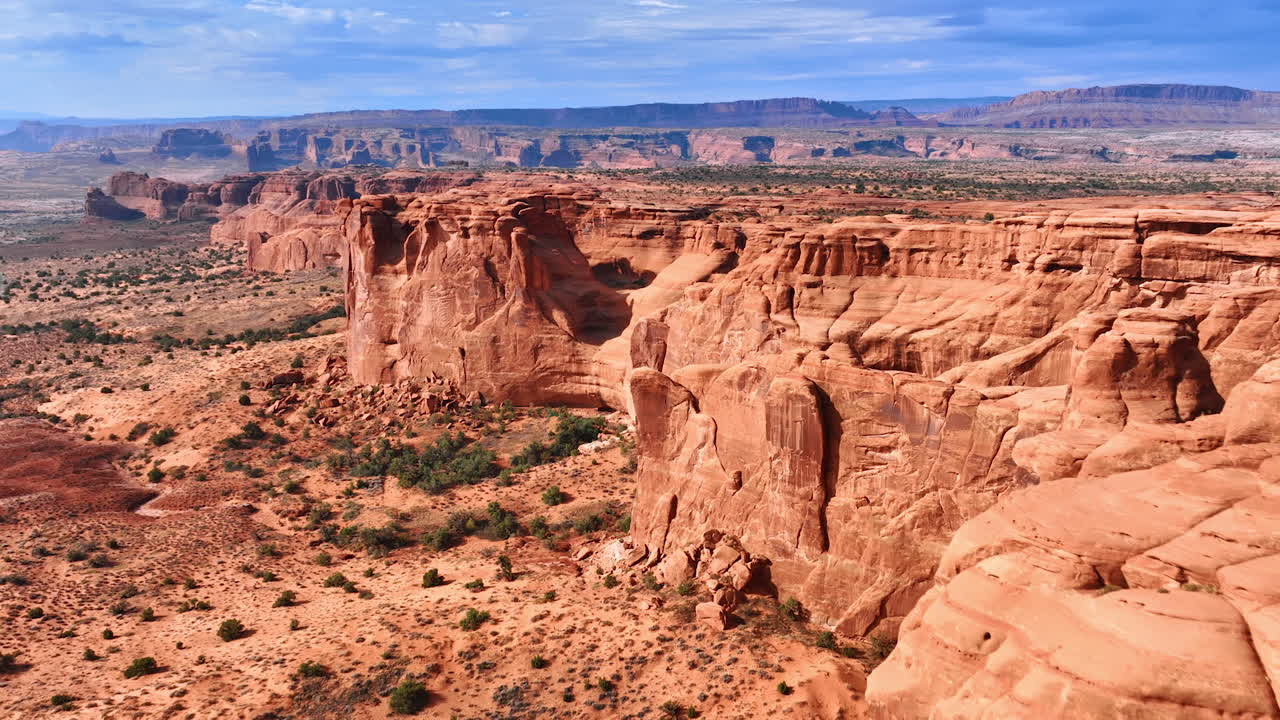 En strålende sol blænder de fantastiske kløfter i Arches National Park, Utah, USA. Droneflyvning nærmer sig klipperne med stejle vægge.