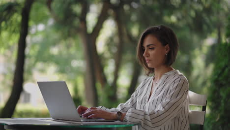 Geschäftsfrau,-Brünett,-Hispanische-Ethnische-Gruppe,-Tippt-Auf-Einem-Laptop,-Während-Sie-An-Einem-Tisch-In-Einem-Sommercafé-Sitzt-Und-Fernarbeit-Erledigt.-Freiberufliche-Frau.-Kleinbetrieb