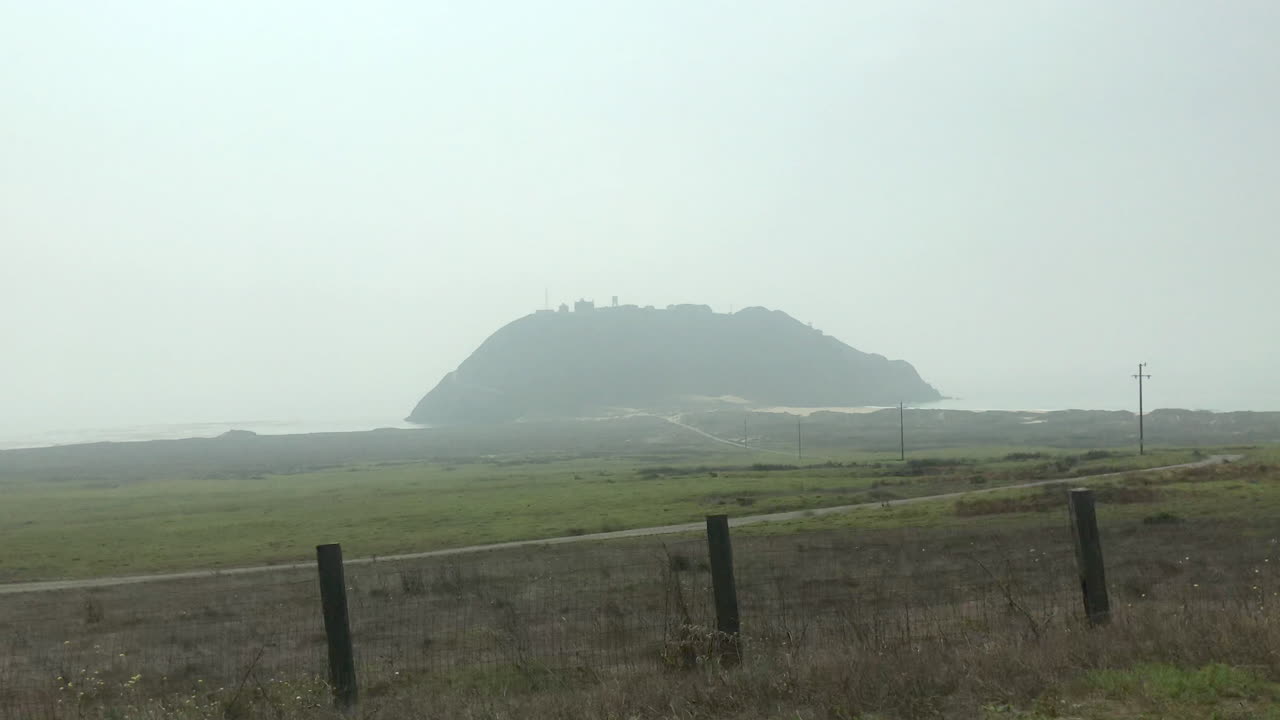 Giant hill in a mirage on the coast in fog while driving by on vacation road trip.