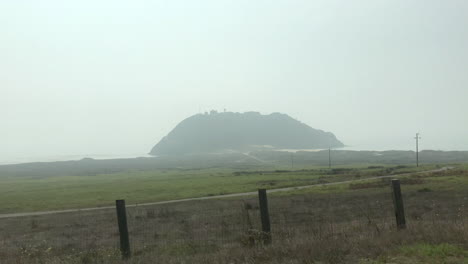 giant hill in a mirage on the coast in fog while driving by on vacation road trip.