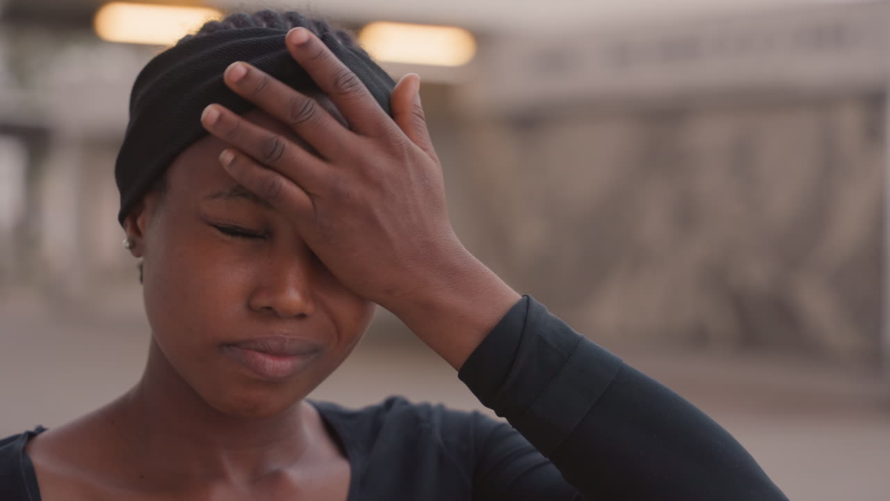 Mulher ao ar livre sente calor e exaustão. Senhora ao ar livre busca conforto em meio ao calor intenso da tarde. Mulher afro-americana sentindo fadiga e desidratação no calor do verão ao ar livre.