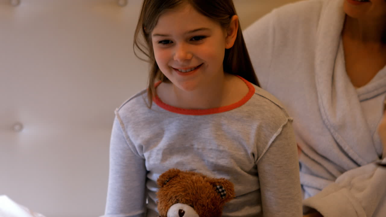 madre peinando el cabello de la hija en la cama