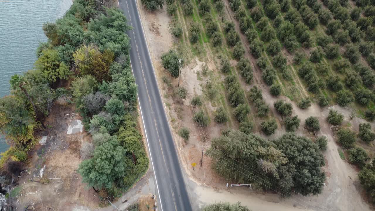 Drone footage looking down on road traveling through farm land and deserted fields