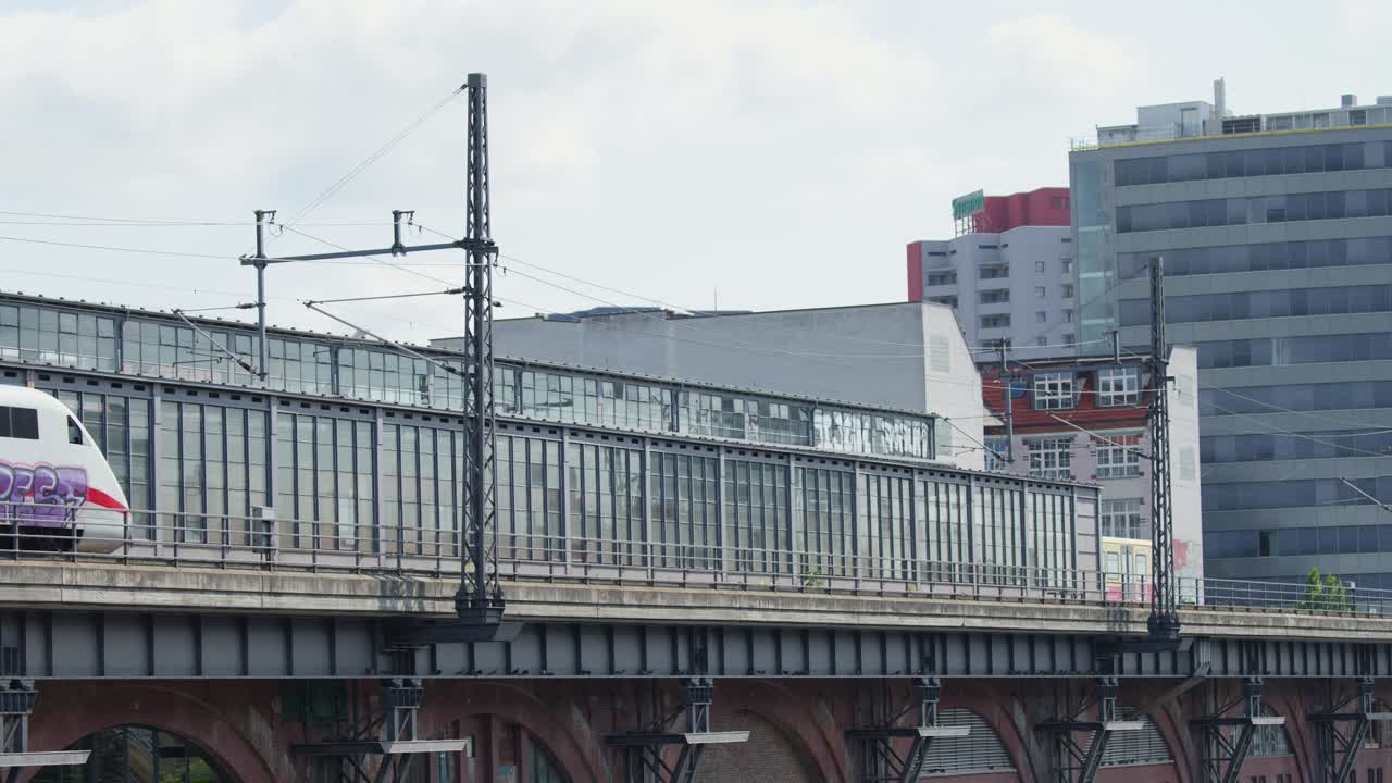 Modern high-speed train travels across elevated railway bridge in Berlin, overcast daylight, static shot