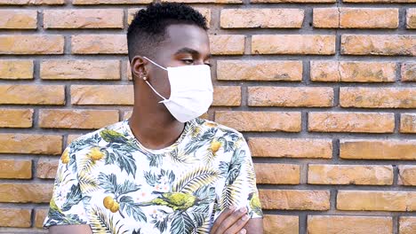 Afro-brasilianischer-Mann,-Der-Sich-Mit-Einer-Covid19-coronavirus-maske-An-Die-Wand-Lehnt,-Deprimiert-Und-ängstlich-Mit-Verschränkten-Armen