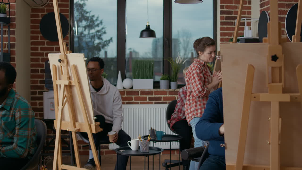 Young artist looking at drawings on canvas in art class