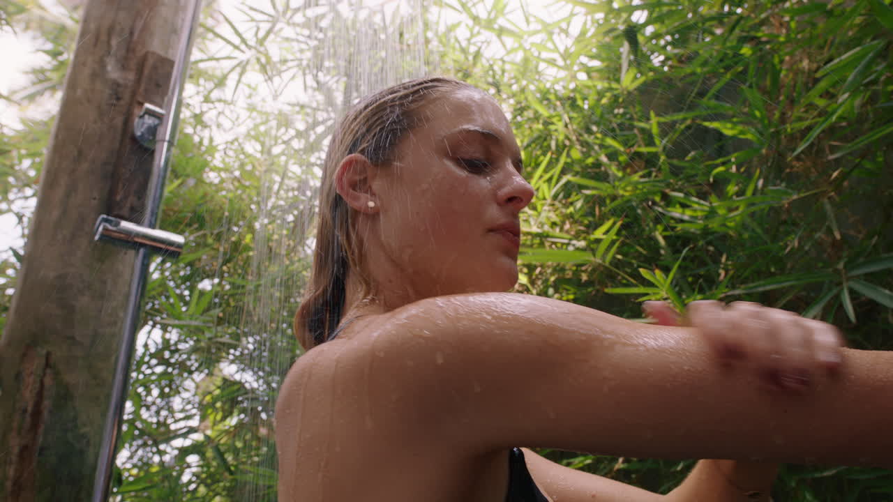 mujer joven en la ducha con bikini lavando el cuerpo con agua refrescante disfrutando de la belleza natural spa duchándose al aire libre en la naturaleza 4k