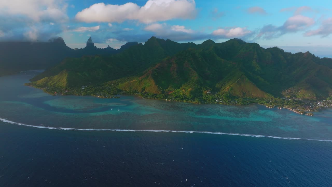 Golden hour sunset Cooks Opunohu Bay Moorea island French Polynesia aerial drone Mount Mauaroa Tohivea Rotui Haapiti jagged mountains boats lagoon coral reef waves windy Pacific Ocean forward motion