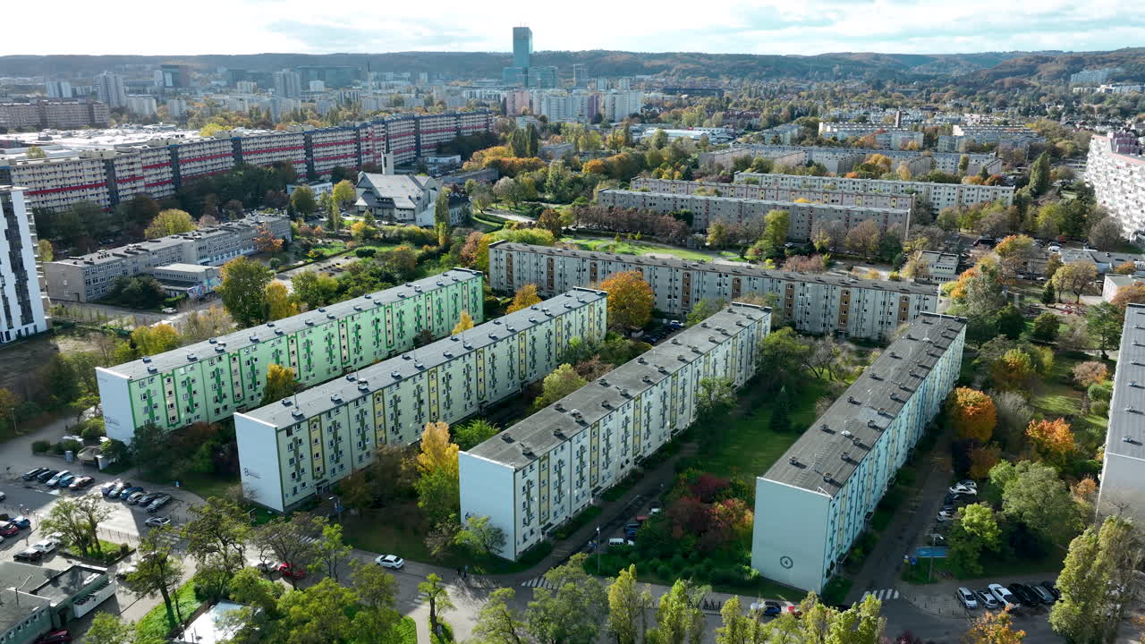 Aerial view of large residential blocks surrounded by trees, roads and dense urban housing districts in Gdańsk