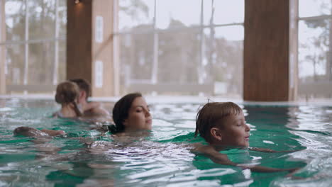 family weekend in hotel with indoor pool children are swimming and parents are watching