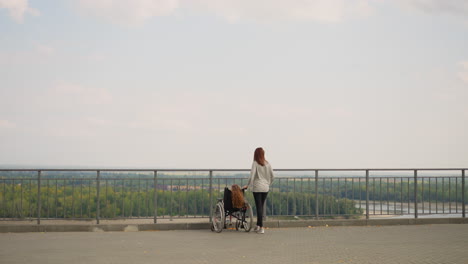 redhead woman and little girl with disability look at river