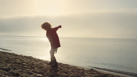 silueta positiva de mujer levantando las manos en la orilla del mar. niña emocional sintiéndose feliz