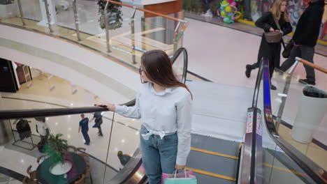 lady on ascending escalator in bustling mall, casually dressed with shopping bags, surrounded by other shoppers in a vibrant retail environment