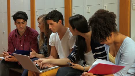 Smiling-students-using-laptop-in-locker-room
