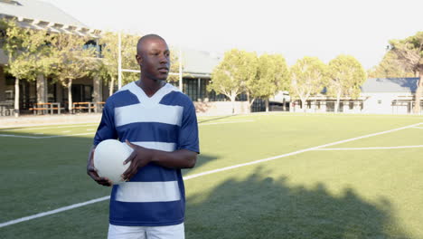 holding soccer ball, african american male athlete standing on field in sports uniform, copy space