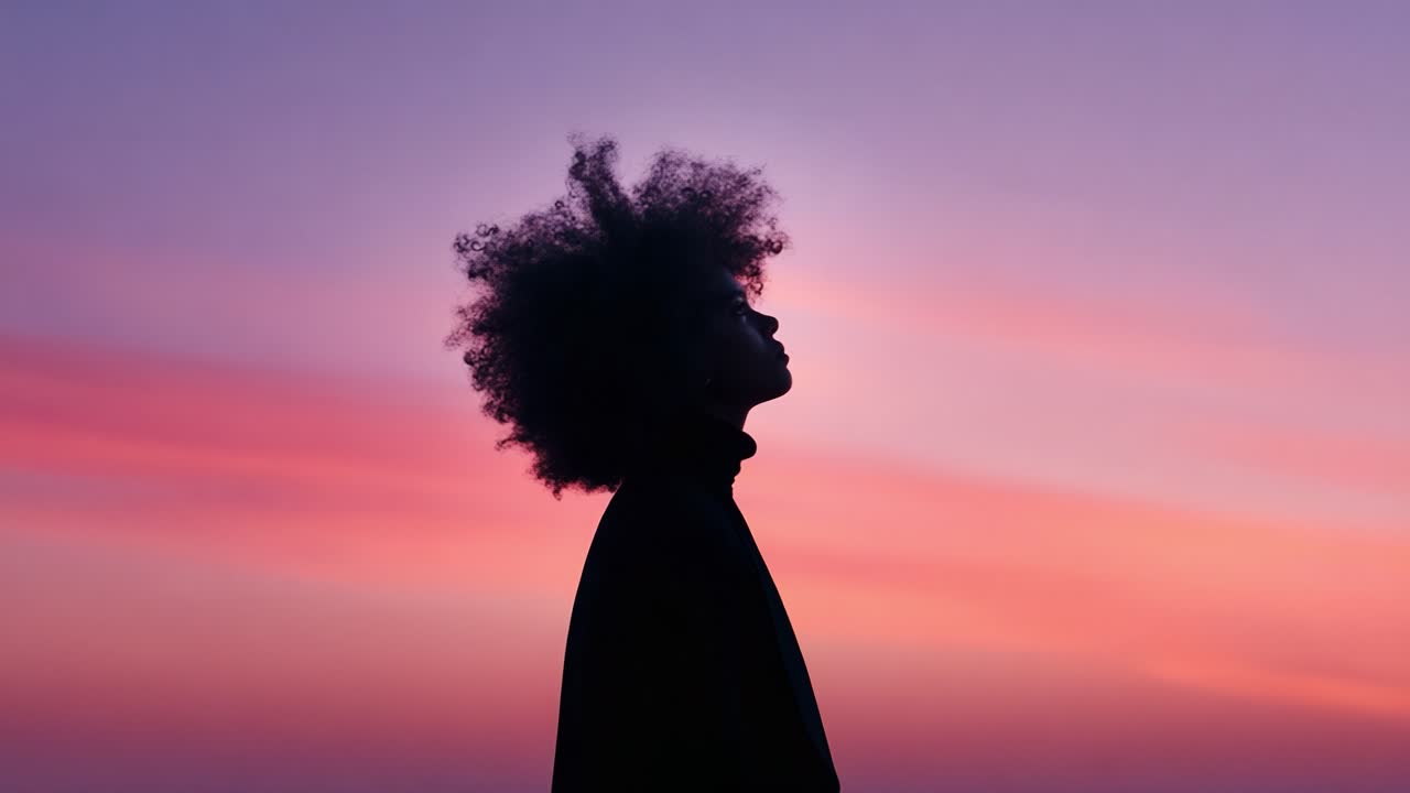 A silhouette of a person with curly hair against a vibrant twilight sky, showcasing a gradient of colors ranging from pink to purple, embodying a peaceful moment of reflection and beauty