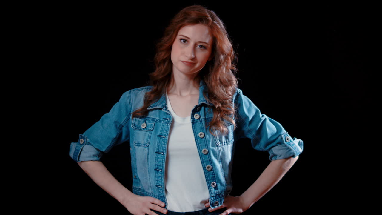 una joven mujer caucásica pone sus manos en sus caderas y sacude la cabeza