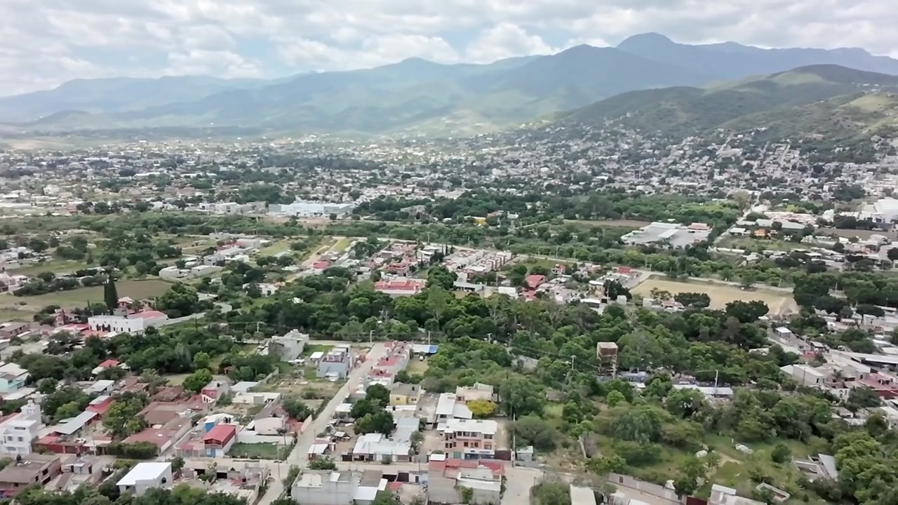Ripresa aerea con drone che mostra il paesaggio urbano residenziale di Huatulco circondato da aree verdi, alberi e paesaggio montano a Oaxaca, Messico, di giorno sotto un cielo nuvoloso