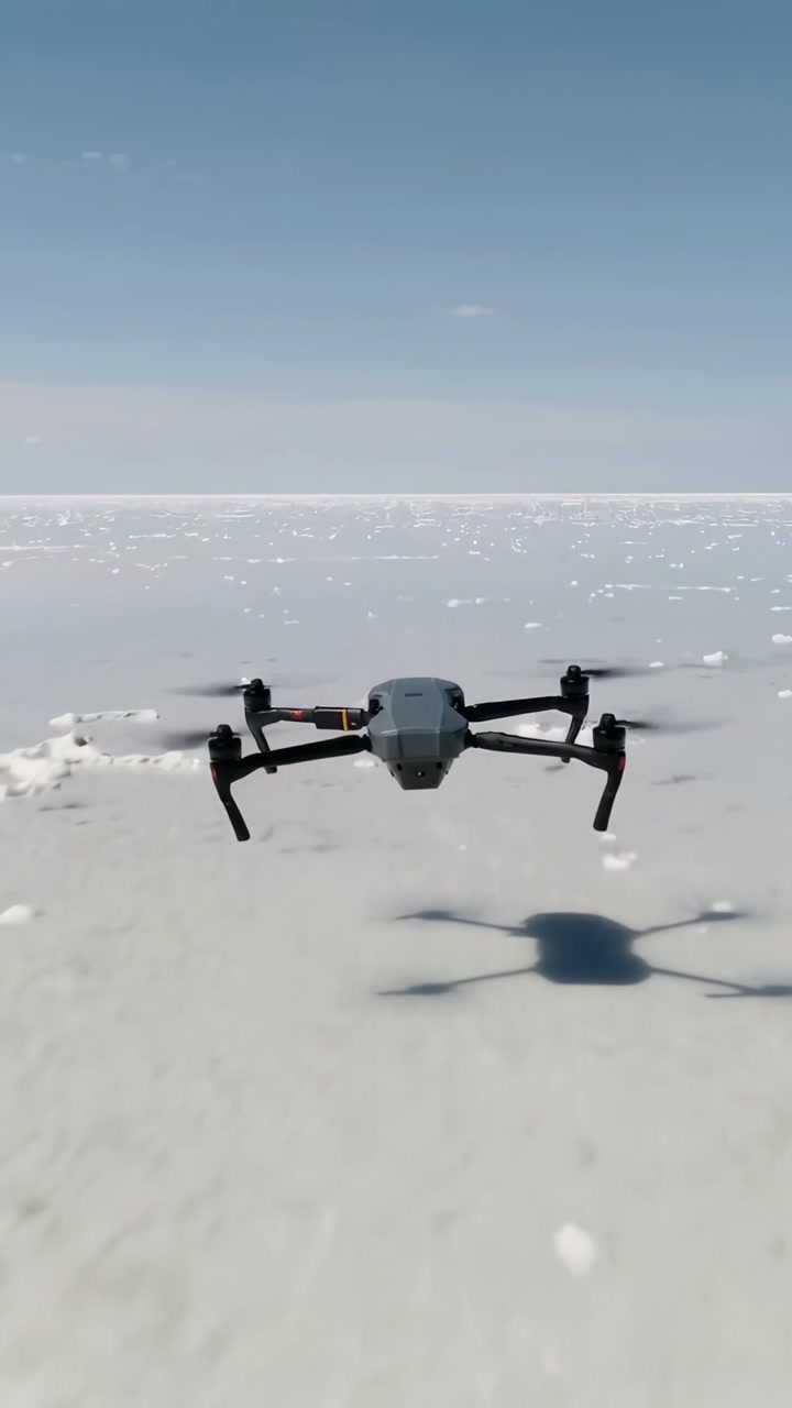 Vertical video: Receiving signal drone hovering over salt flat with rotor blur, capturing footage