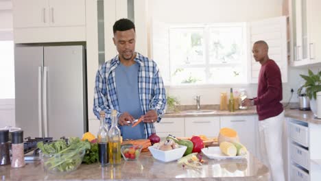 feliz pareja afroamericana gay preparando la cena, bebiendo vino en la cocina, cámara lenta