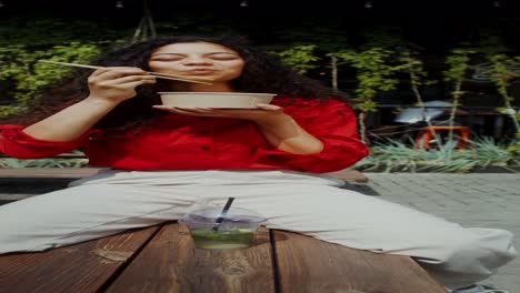 woman eating noodles outdoors