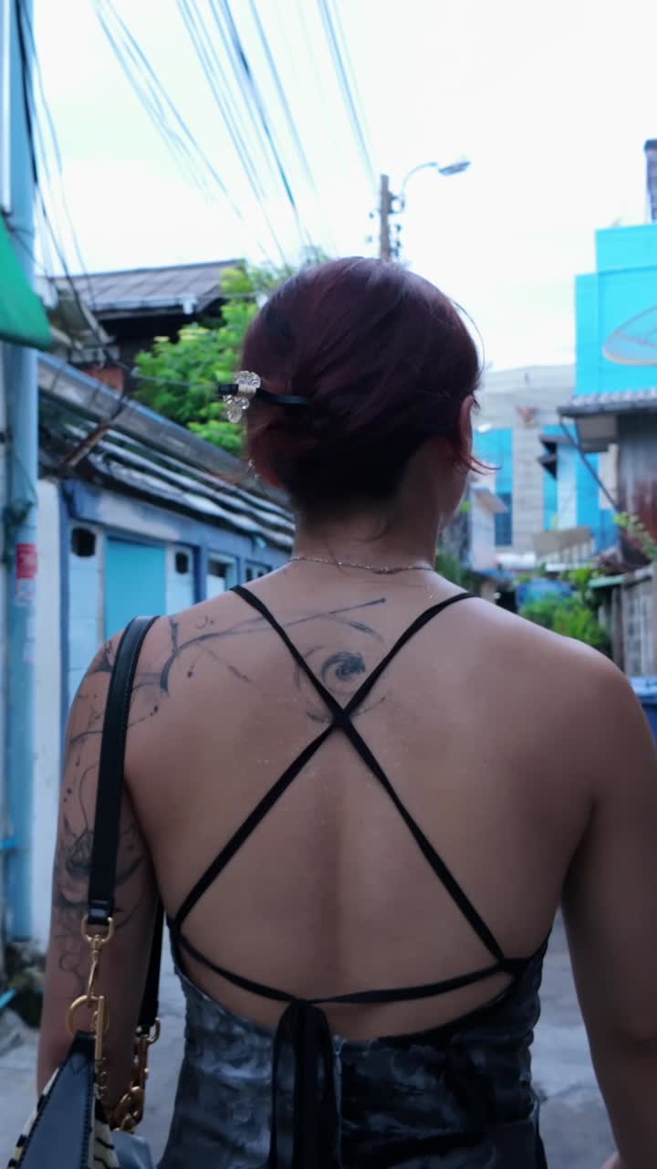 Woman with back tattoo in alleyway